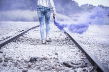 a woman carrying a blue smoke flare 