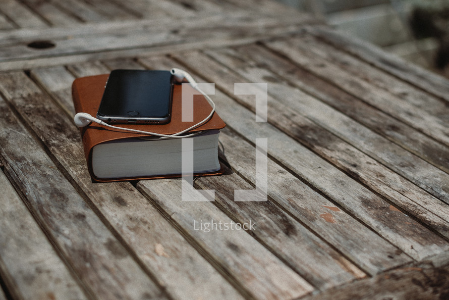 smartphone, earbuds, and a Bible 