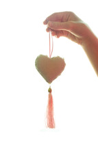hand holding a heart ornament with a tassel 