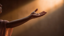 An outstretched hand reaches into the sunlight, 