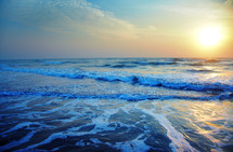 tide washing onto a shore at sunrise 