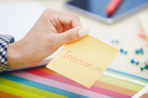 woman holding a sticky note with the word innovation 