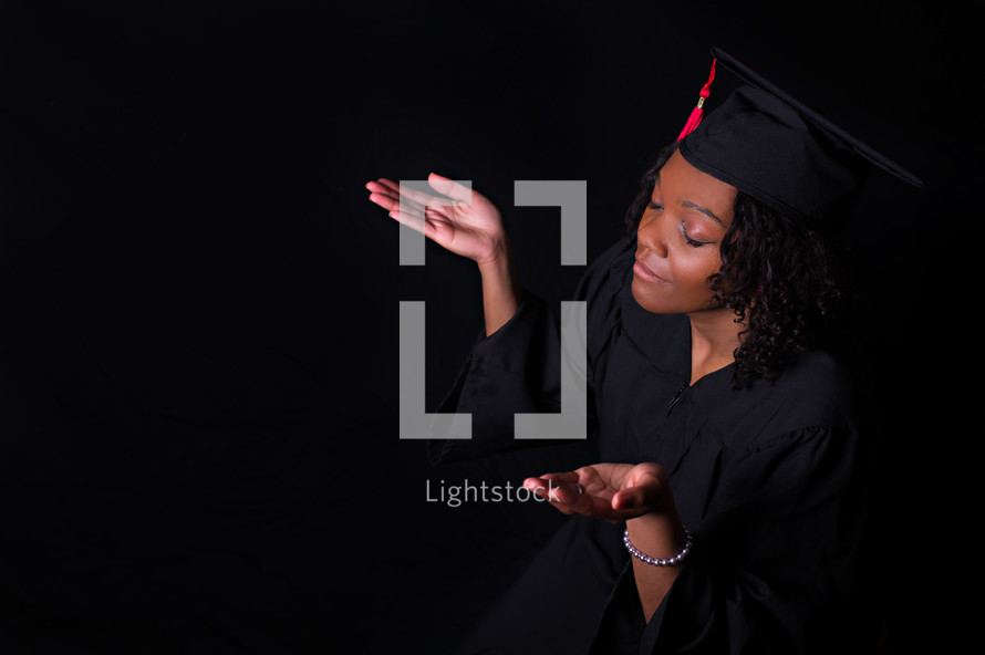 an African American woman graduate with raised hands 