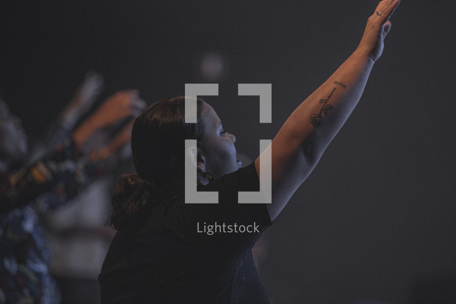 woman with hand raised at a worship service 