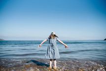 a girl standing in the ocean getting her feet wet 