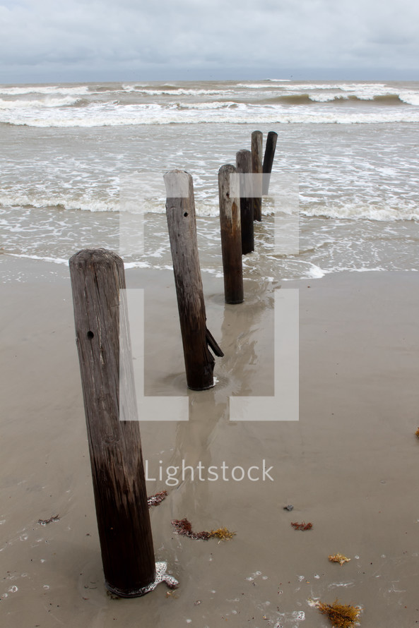 old pier pilings in the sand 