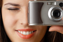 Smiling model with closed eye making photo using digital camera