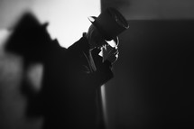 a man in a top hat standing in the shadows 
