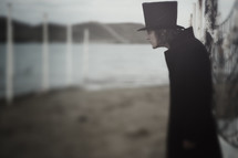 man in a vintage top hat and black trench coat 