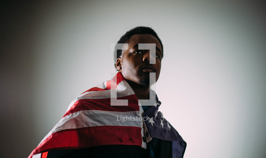 An African American man wrapped in an American flag 