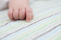 infant's hand on a blanket 