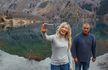 woman talking a selfie standing outdoors by a pond