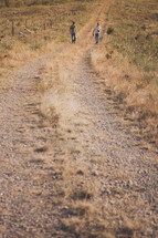 Two men wakling uphill on a dirt road.
