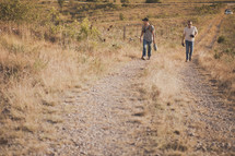 Two men walking up a hill on a dirt road.