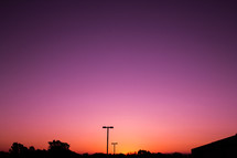 silhouettes of street lamps against a pink sky at sunset 