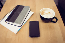 Bible, notebook, cellphone, and coffee cup on a wood table 