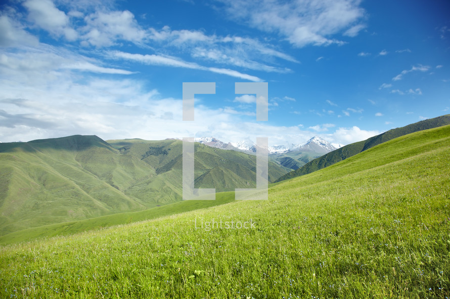 snow capped mountains and green rolling hills 