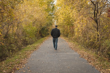 a man walking on a paved path in fall 