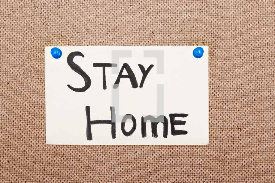 Adhesive note with Stay Home text on a bulletin board