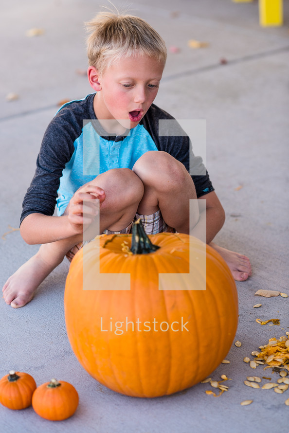 a boy child carving a pumpkin 