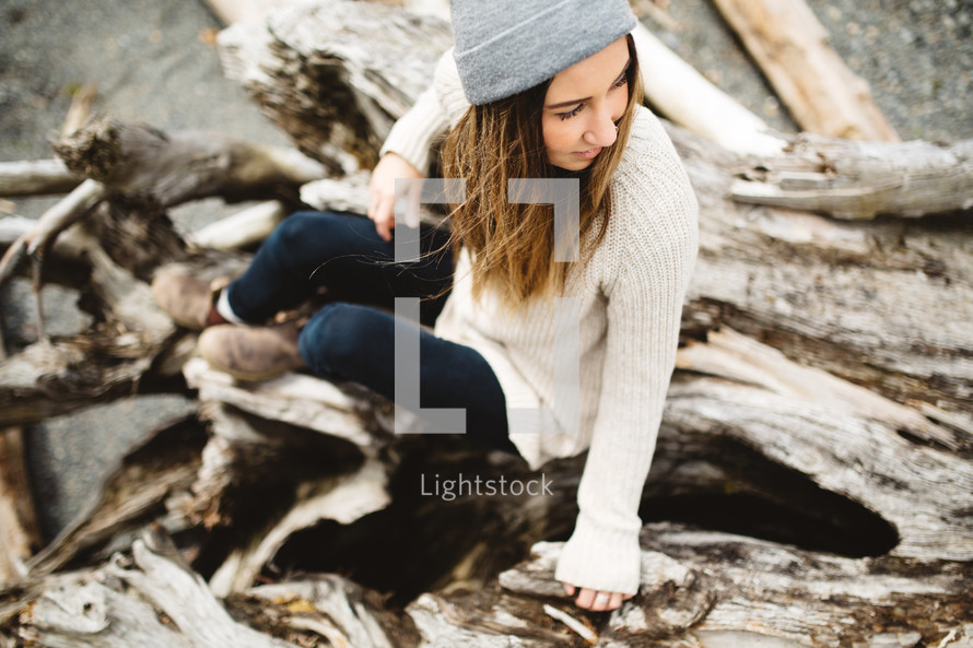 woman sitting on driftwood 
