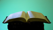 an open Bible on a stack of Bibles 