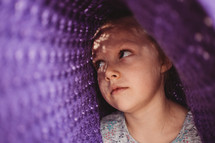 little girl hiding under a blanket 