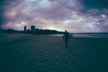 Surfboarder on the beach at dusk.