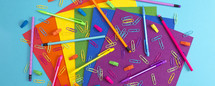 pencils, erasers, paperclips, and paper in rainbow colors 