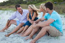 couples sitting together talking on a beach 