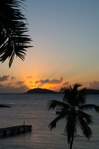 sunbeams behind a tropical island at sunset 