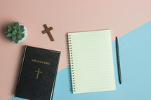 Bible and notebook on a pink and blue background 