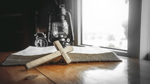 wooden cross in front of an open Bible 