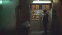 a man standing in front of a doorway in a dark hallway