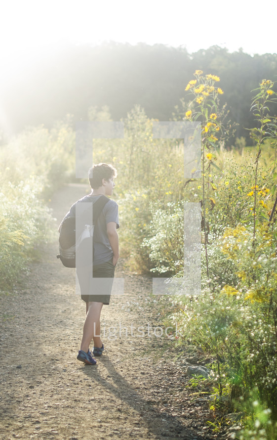 a teen boy walking on a path 