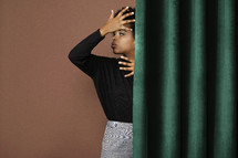a woman standing behind a curtain 