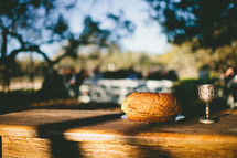 sunlight on an outdoors table with communion bread and wine 