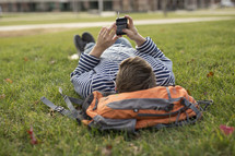 a college student lying in the grass listening to a podcast 