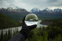 a man holding out a crystal ball in front of a mountain scene 