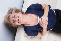 woman laughing and texting on a white couch 