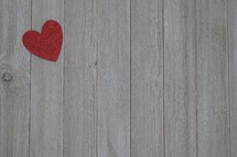 a single red heart on a gray wood boards 