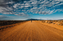 man standing in the middle of a dirt road 