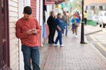 man texting on his phone standing on a sidewalk 