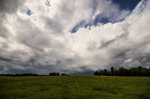 clouds over a green field 
