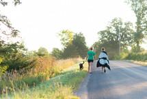 women walking down a country road walking a dog 
