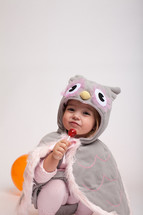 a girl toddler in a Halloween costume with a sucker 