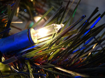 Close up of golden white Christmas tree light against pine needles on Christmas tree