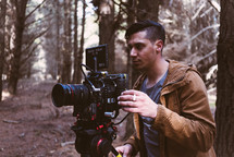 man standing in the woods with a video camera 