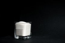 sugar in a transparent glass with a corrugated face on a black background