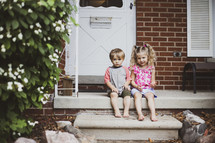 kids sitting on steps on a front porch 